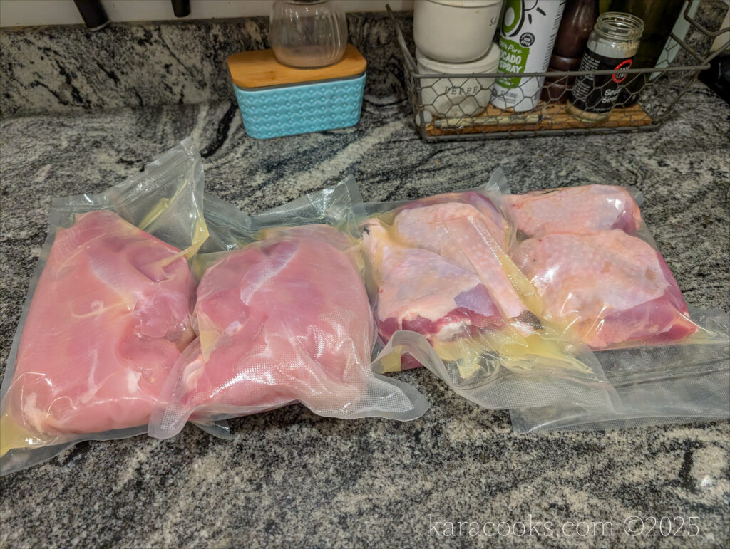 Four vacuum sealed bags with turkey breasts, thighs, and legs are sitting on the counter waiting to be sous-vide cooked.